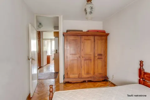 Spavaća soba sa drvenim ormanom, krevetom i otvorenim vratima koja vode u hodnik. - image 10