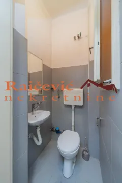 Manje kupatilo sa lavaboom, wc šoljom i sivim pločicama. - image 18