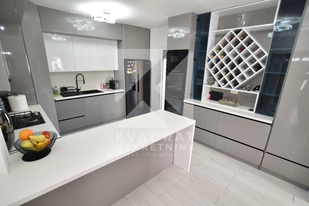 Modern kitchen with an island, built-in appliances, and a built-in wine rack.