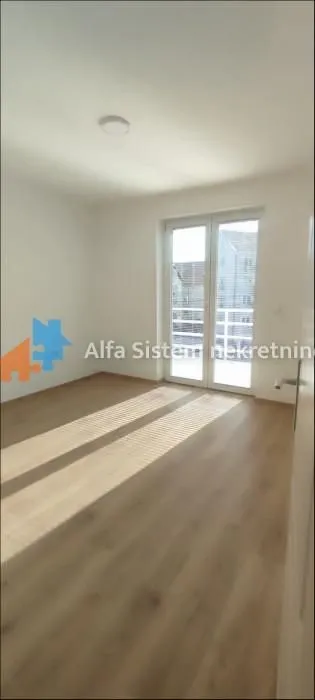 Empty room with laminate flooring and balcony doors.