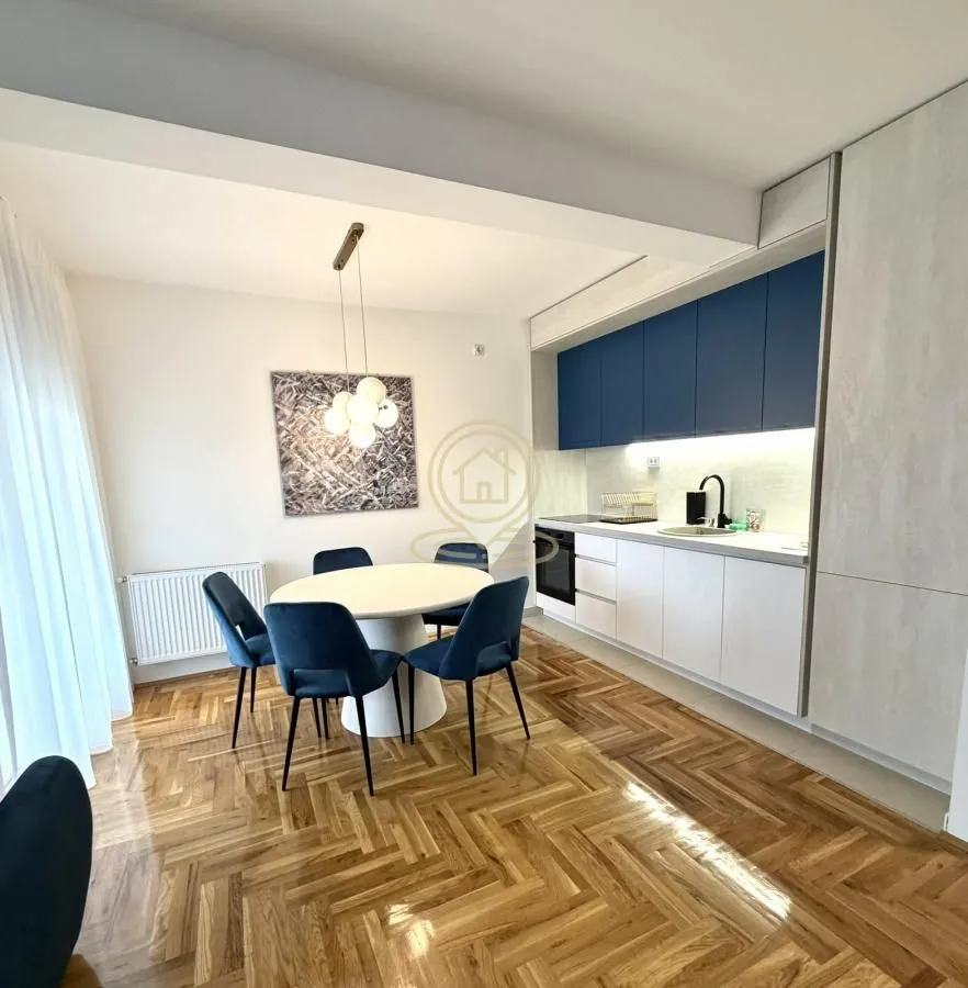 Modern kitchen with a dining area and parquet flooring.