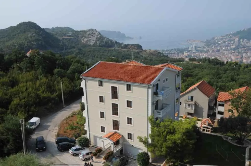Pogled iz ptičje perspektive na stambenu zgradu okruženu zelenilom sa pogledom na more.
