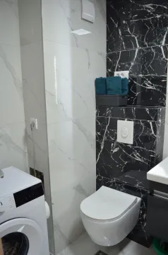 Moderne kupatilo sa bijelim i crnim mermernim pločicama, konzolnom šoljom i veš mašinom. - image 7