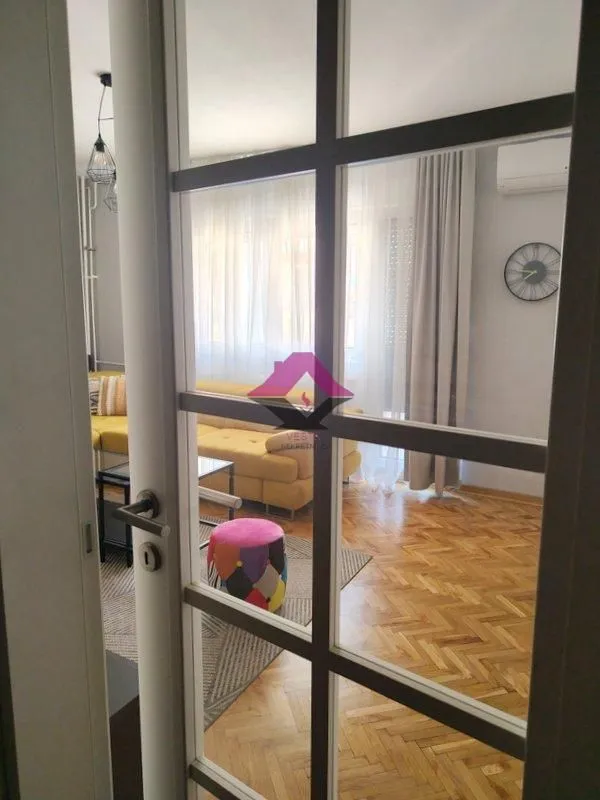 A view through glass doors into a bright living room with a sofa.