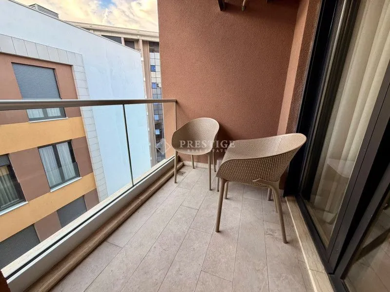 Covered balcony with seating set and a view of surrounding buildings.