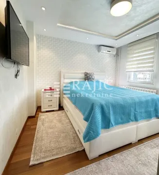 Furnished bedroom with a double bed, TV, and a rug. - image 6