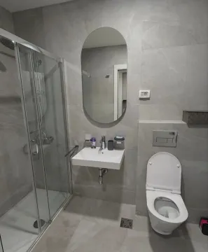 Moderno opremljeno kupatilo sa tuš kabinom, umivaonikom i toaletom u sivoj keramici. - image 7