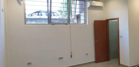An empty room with light walls, a high window, and an open door. - image 3