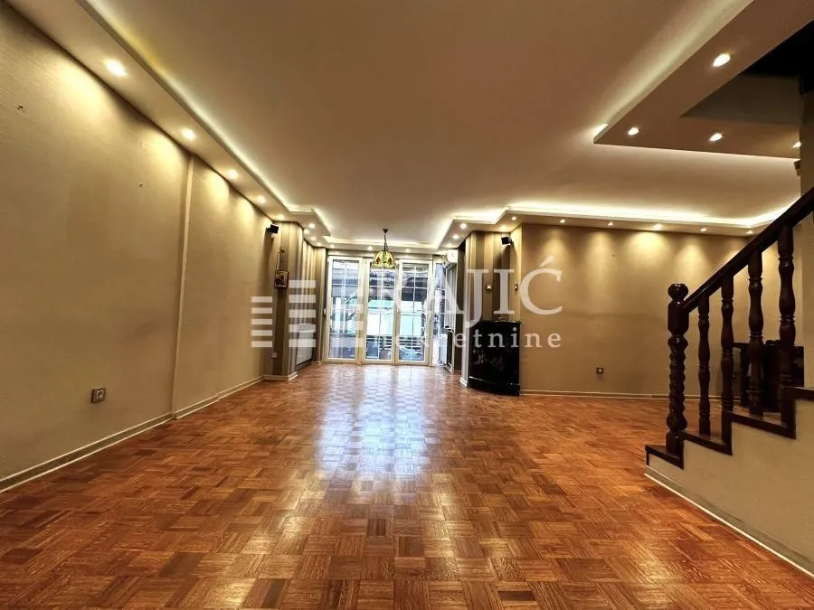 Empty living room with parquet flooring and dropped ceiling with lighting.