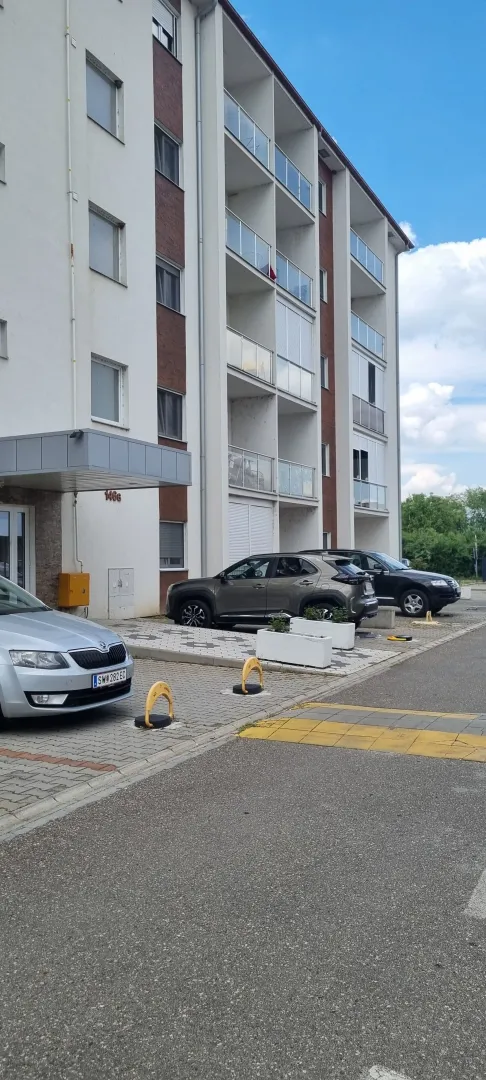 Spoljašnji izgled stambene zgrade sa parkingom.