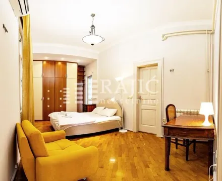 Spacious bedroom with a double bed, desk, and a yellow armchair. - image 16