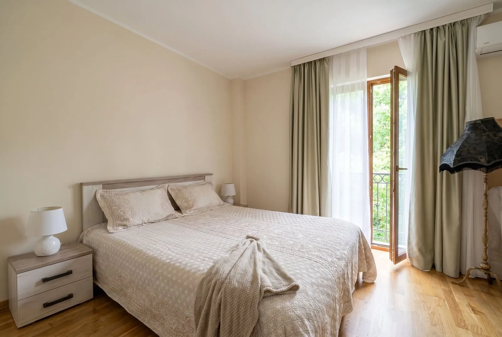 Svijetla spavaća soba sa bračnim krevetom i izlazom na balkon.