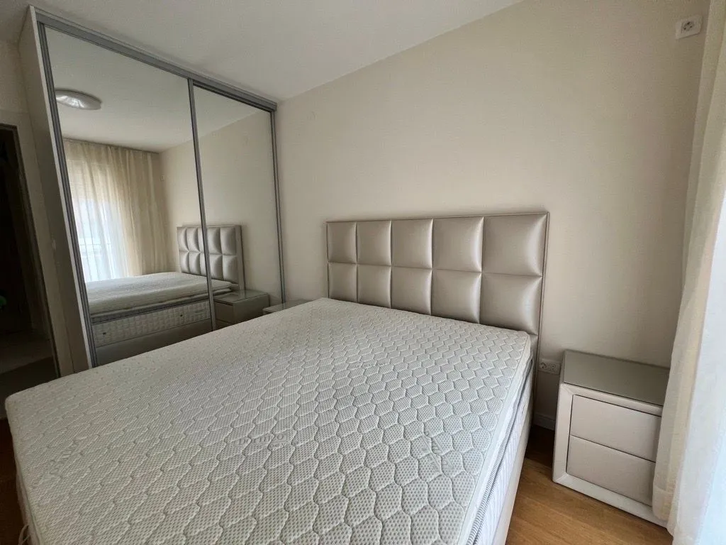 Furnished bedroom with a double bed and a large built-in wardrobe with a mirror.