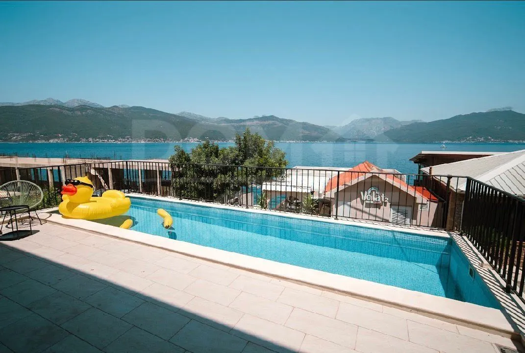 Terrace with swimming pool and view of the sea and mountains.