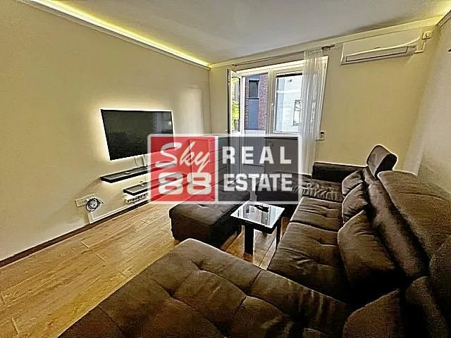 Comfortable living room with a large sectional sofa, TV, and air conditioning unit.