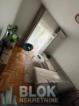 Living room with a sofa, coffee table and balcony access. - image 6