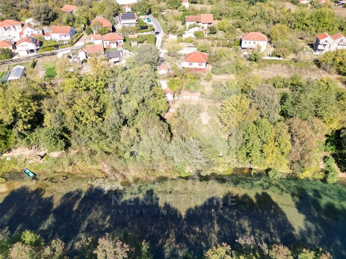 Pogled iz vazduha na imanje sa zelenilom, rijekom i okolnim naseljem.