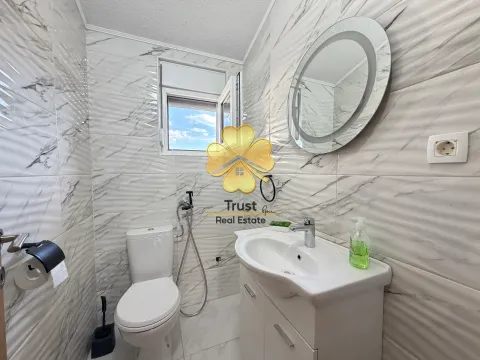 Smaller bathroom tiled with marble-pattern tiles, featuring a sink and toilet. - image 21