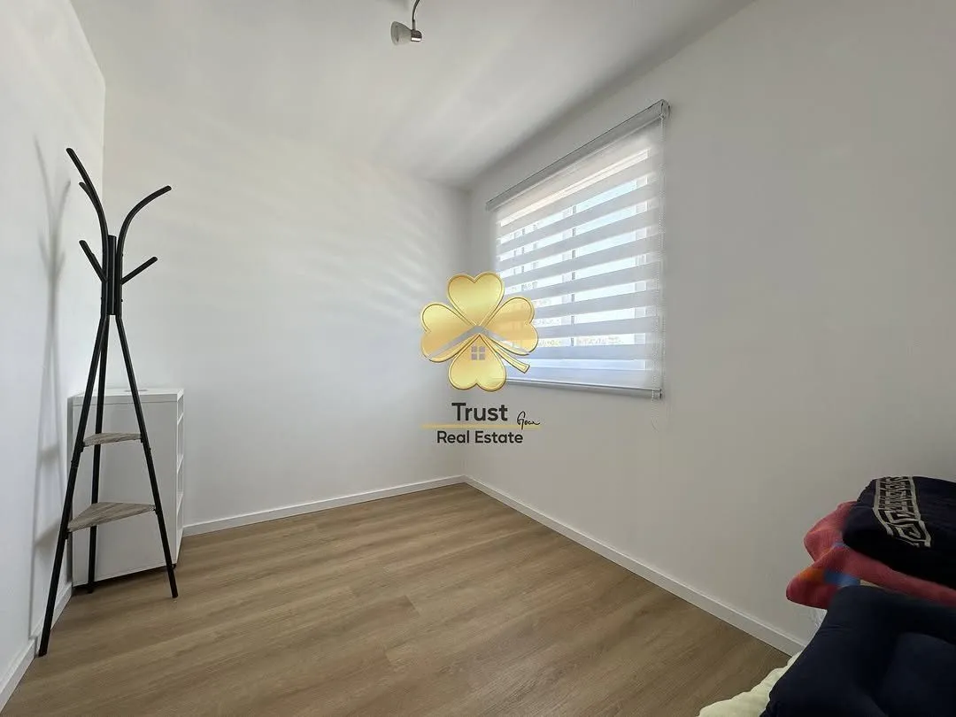 Empty room with laminate flooring and a clothes rack.