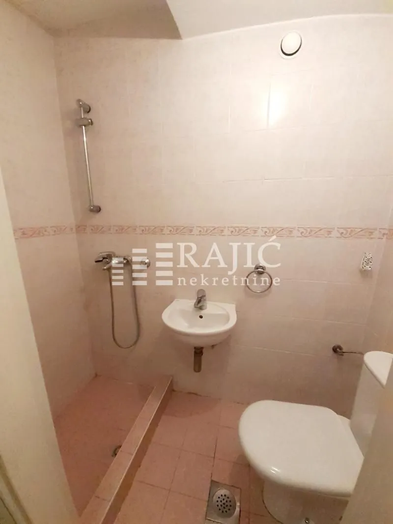 Smaller bathroom with a walk-in shower area, washbasin, and toilet.
