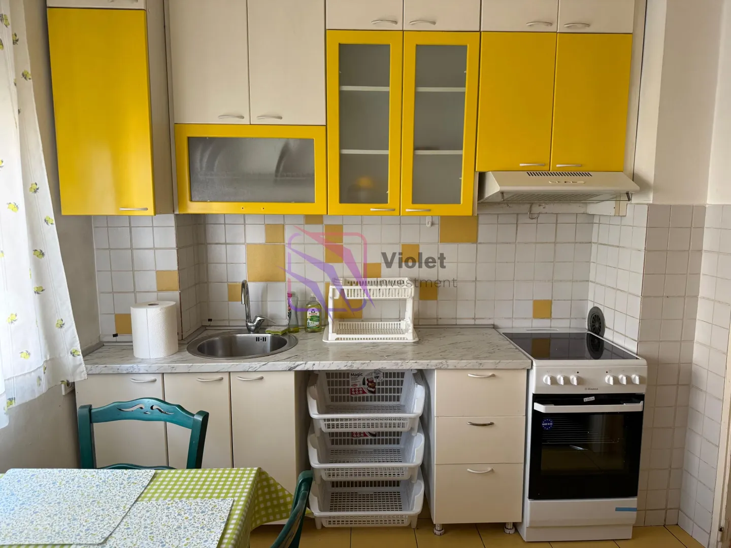 Small kitchen with yellow and white cabinets, a sink, and a stove.