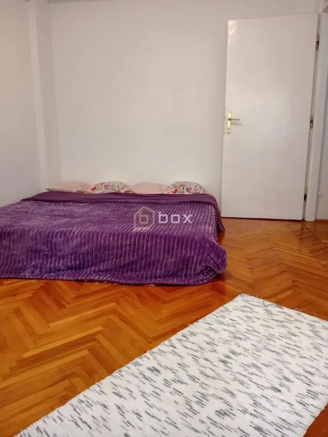 Spavaća soba sa krevetom i parketom na podu.