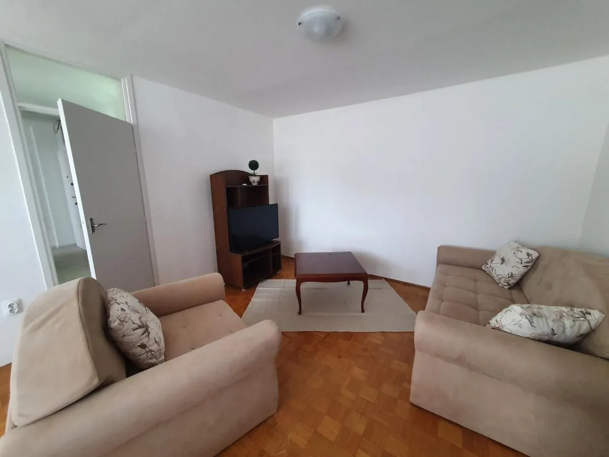 Dnevna soba sa garniturom za sedenje, stočićem i televizorom.