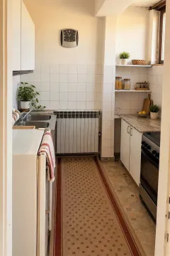 Manja opremljena kuhinja sa bijelim elementima i dužom stazom na podu. - image 10