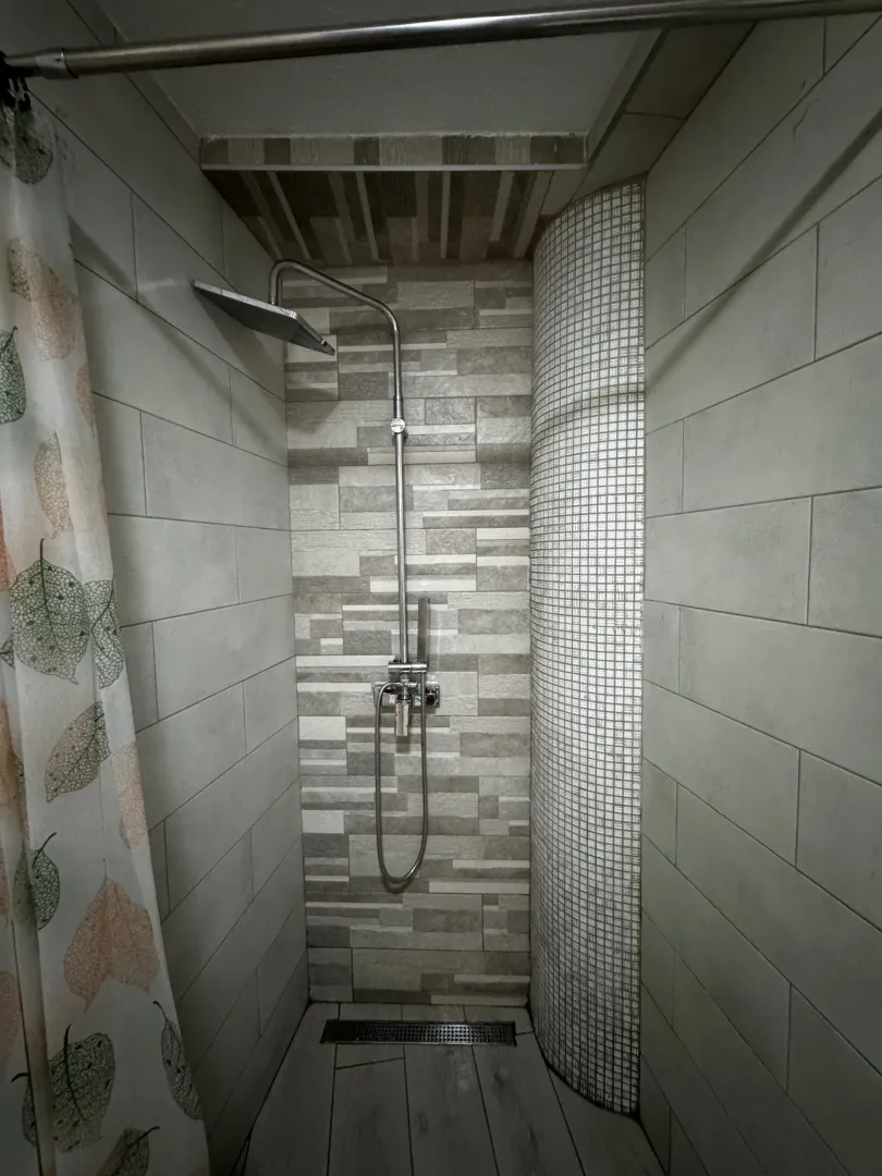 Shower cabin with ceramic tiles and a shower set.