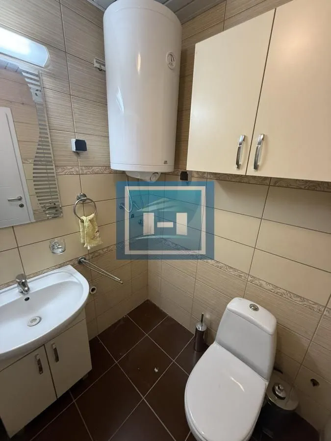 Bathroom equipped with a washbasin, toilet bowl, water heater, and wall cabinet.