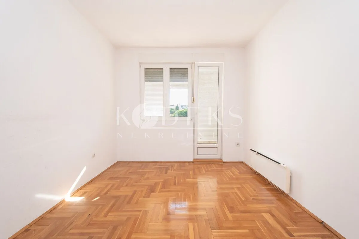 Empty room with white walls, parquet flooring, and access to the terrace.