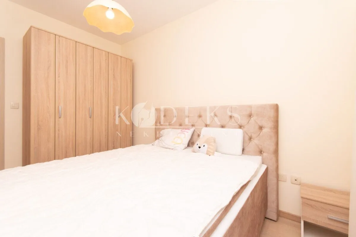 Furnished bedroom with a double bed and a wooden wardrobe.