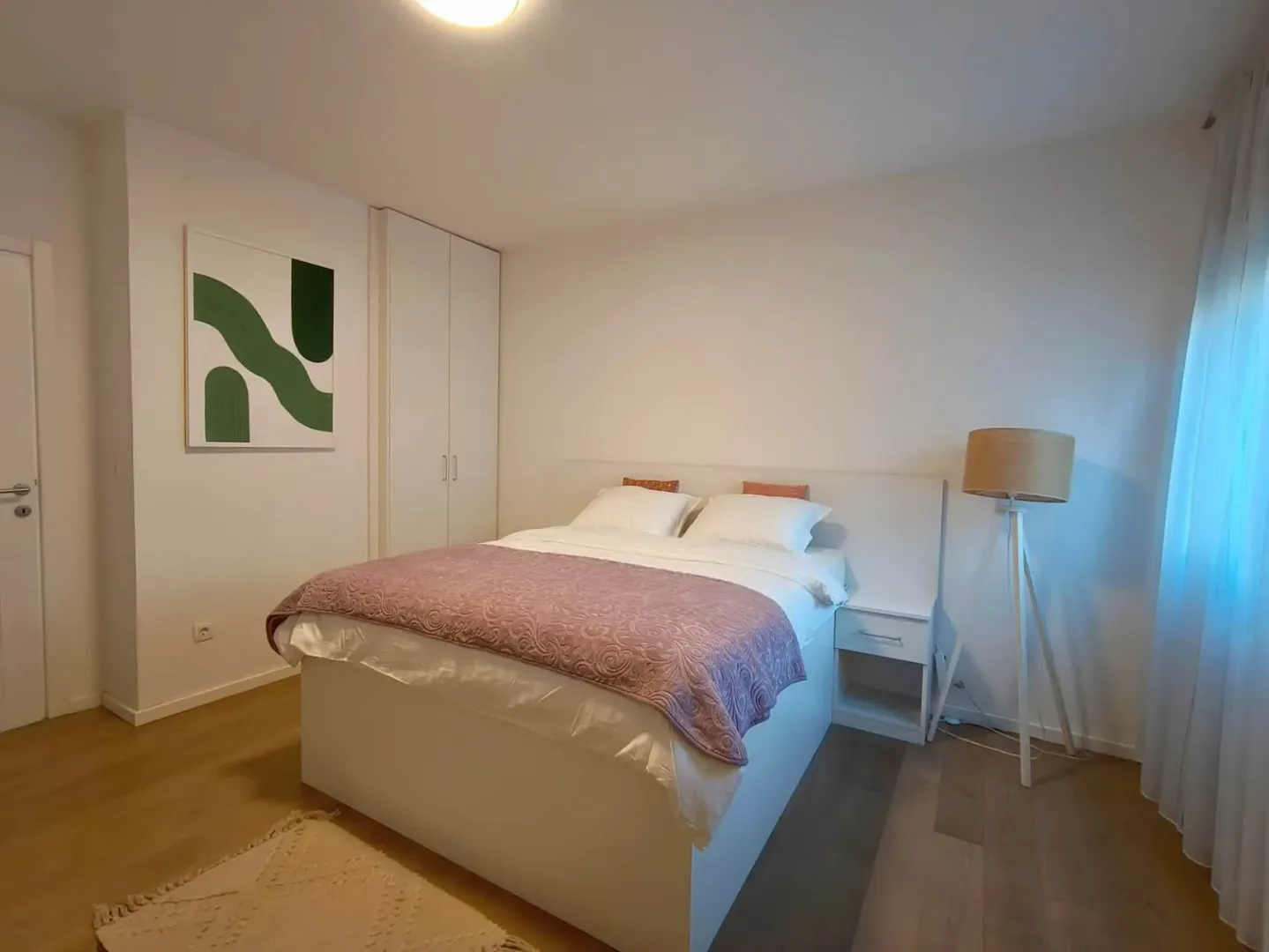 Furnished bedroom with a double bed, wardrobe, and floor lamp.