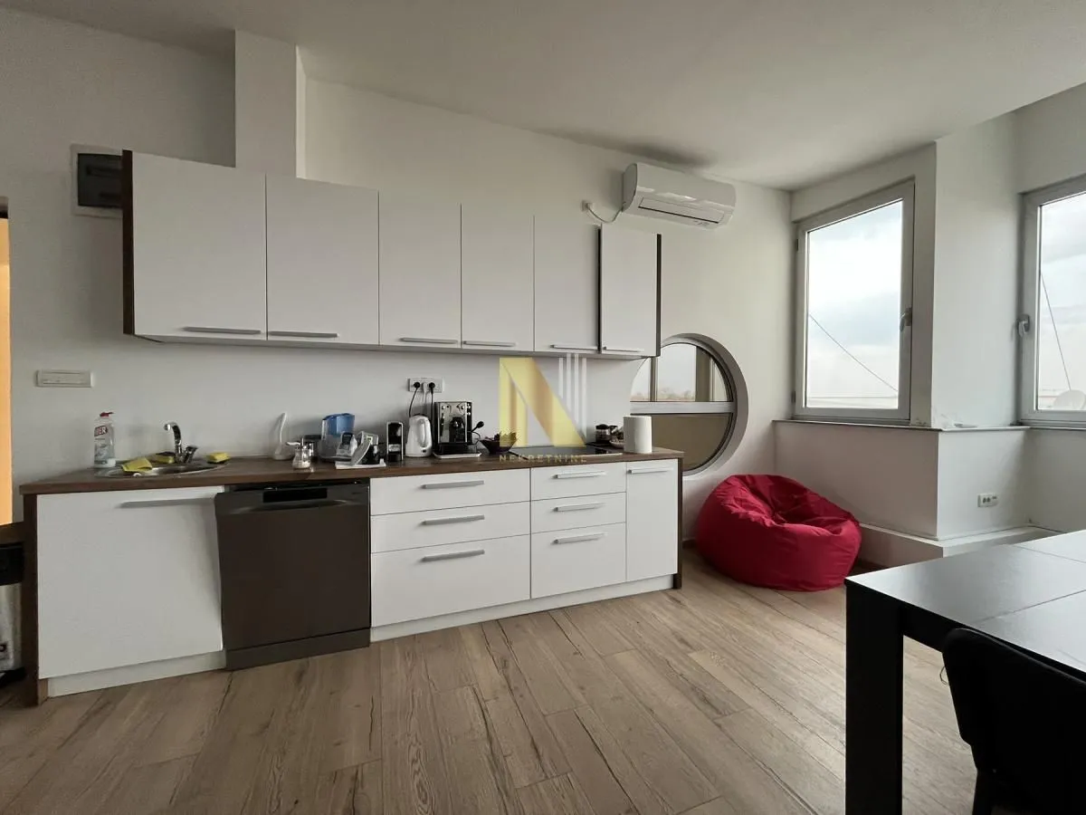 Modern kitchen with white cabinetry and a dining area.