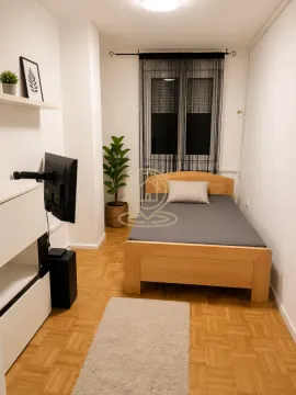 Manja spavaća soba sa drvenim krevetom, televizorom i prozorom. - image 9