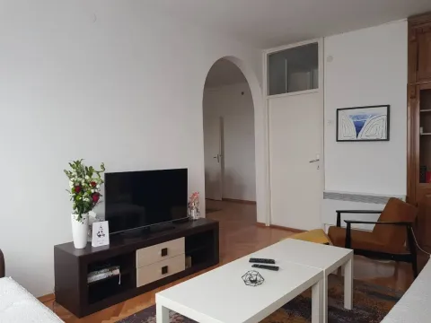 Bright living room with a TV, coffee table, and an armchair. - image 6