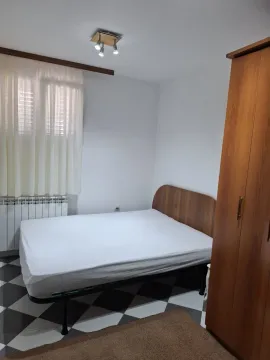 Bedroom with a double bed, wardrobe, and a window with white curtains. - image 4