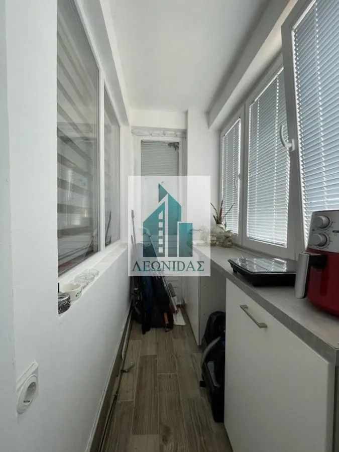 Zastakljeni balkon sa elementima za odlaganje i kuhinjskim aparatima.