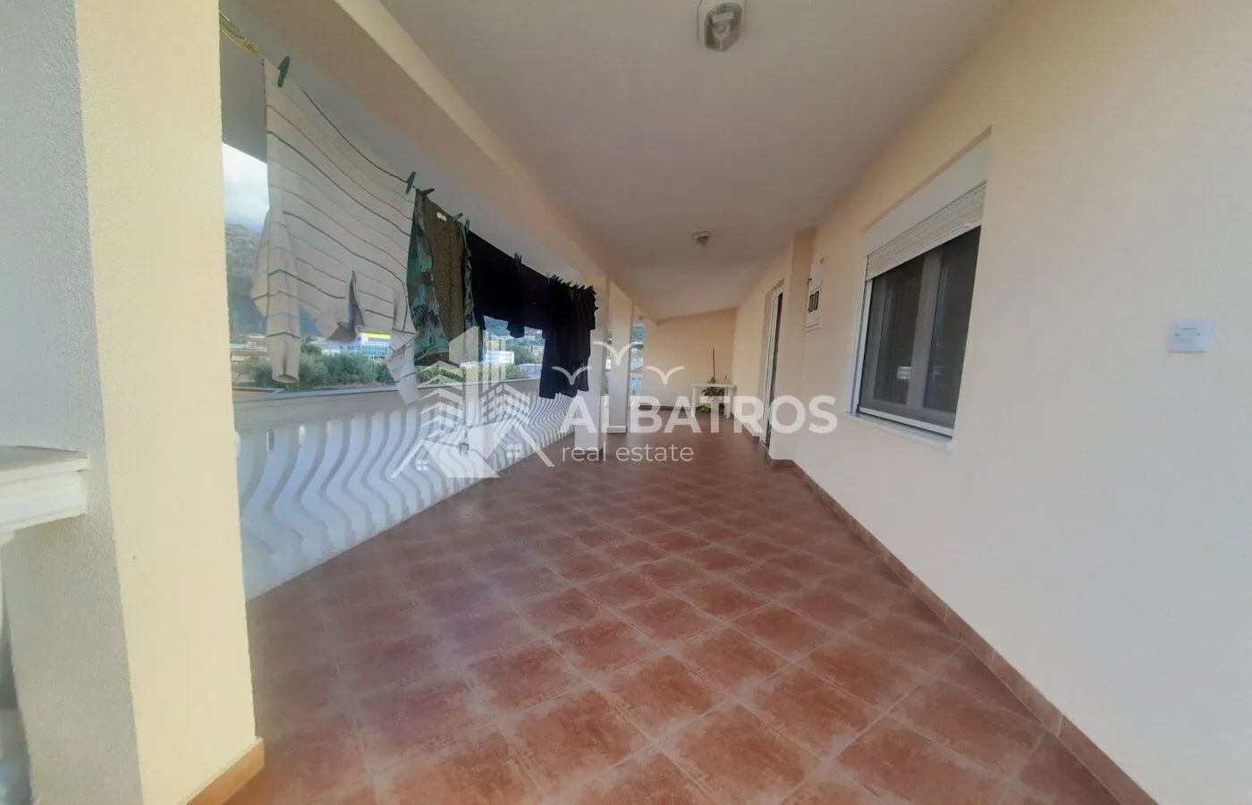 Spacious covered terrace with ceramic tiles and laundry hanging out to dry.