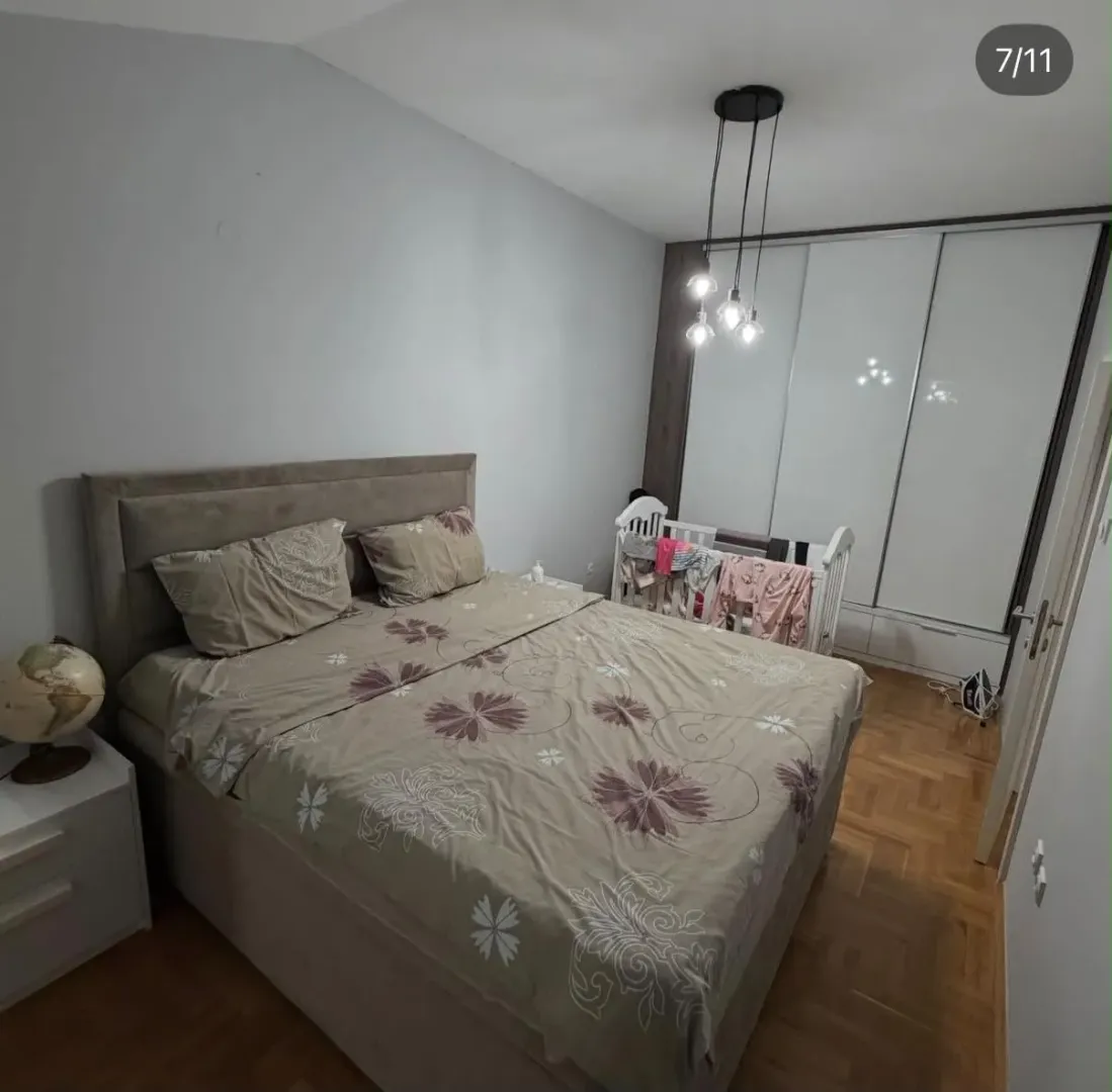 Furnished bedroom with a double bed, wardrobe, and a baby cot.