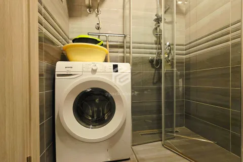Bathroom with a shower cabin and a washing machine. - image 11