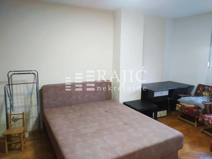 Furnished bedroom with a double bed and a desk.