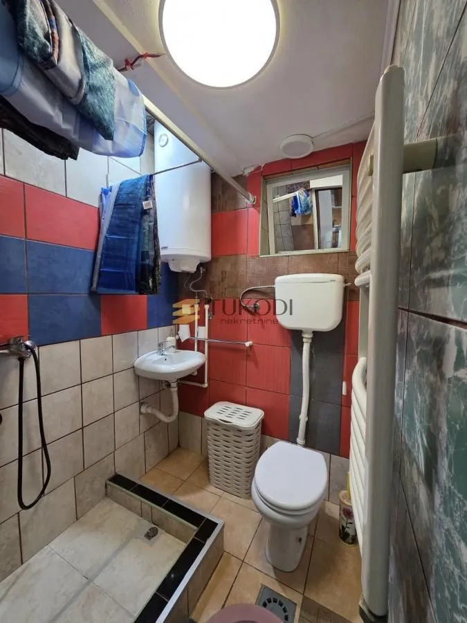 Small bathroom with a shower cabin, toilet, sink, and water heater.