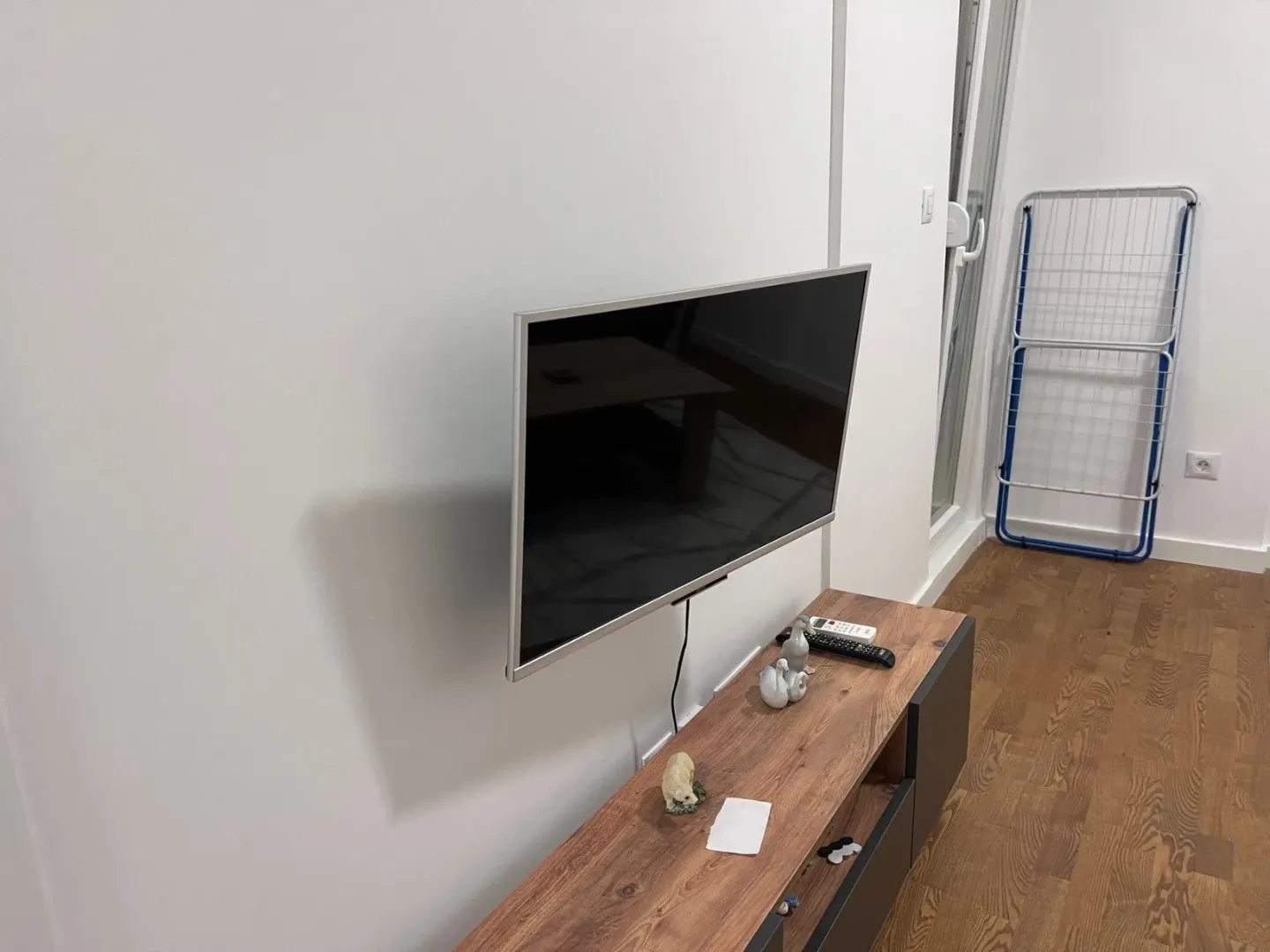 Televizor postavljen na zid iznad komode u dnevnoj sobi.