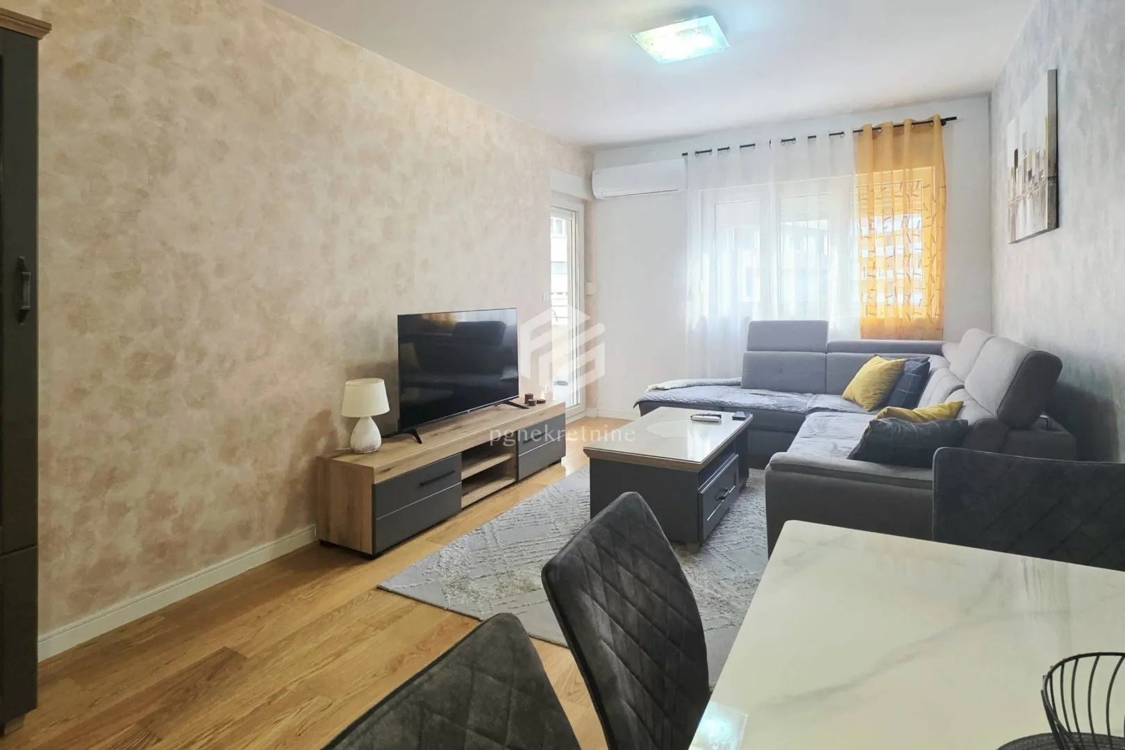 Living room with sofa, TV unit and dining table.