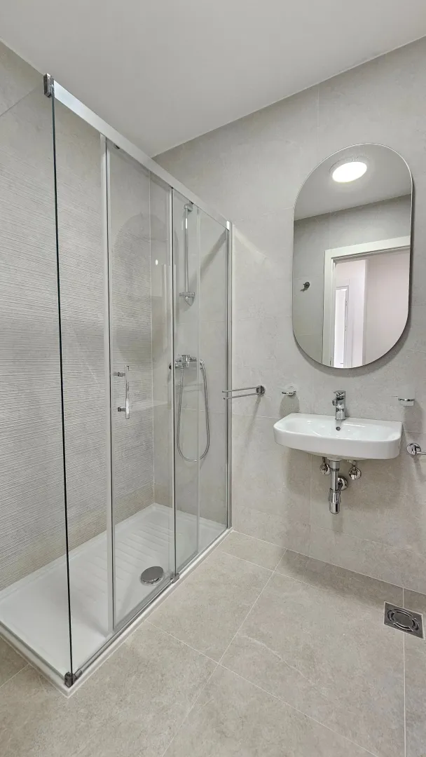 Modernly equipped bathroom with a shower cabin and a sink.