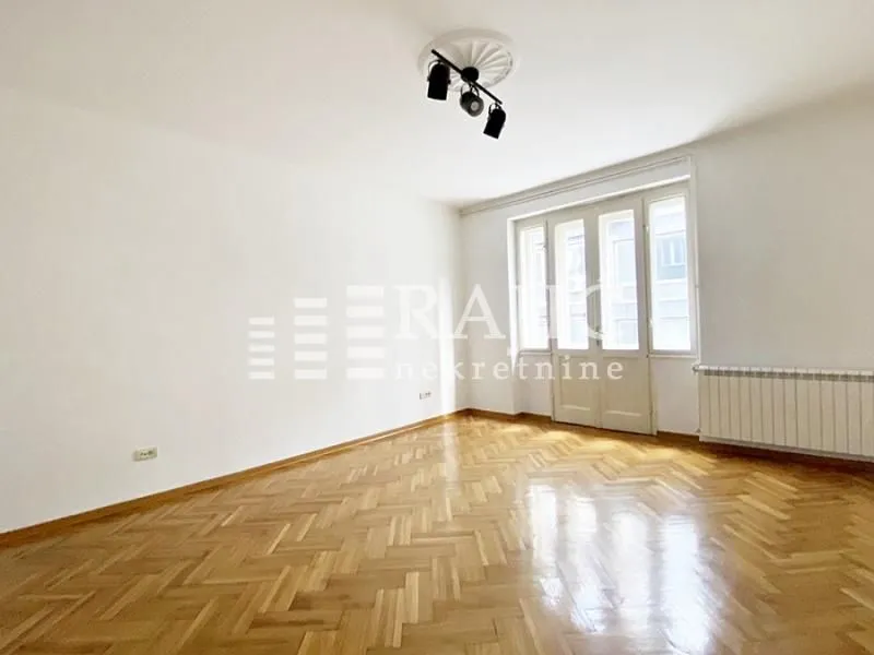 Empty room with parquet flooring and balcony doors.