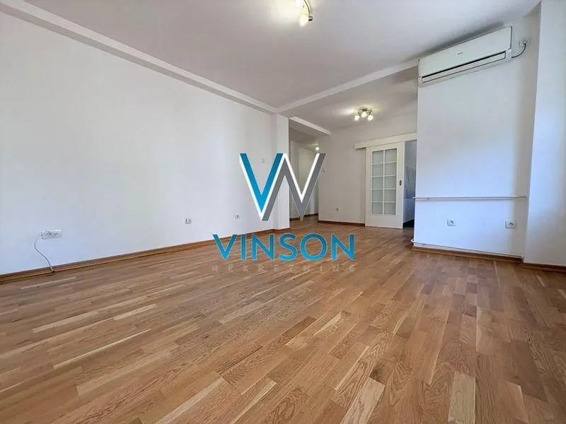 Empty living room with hardwood floors and air conditioning.