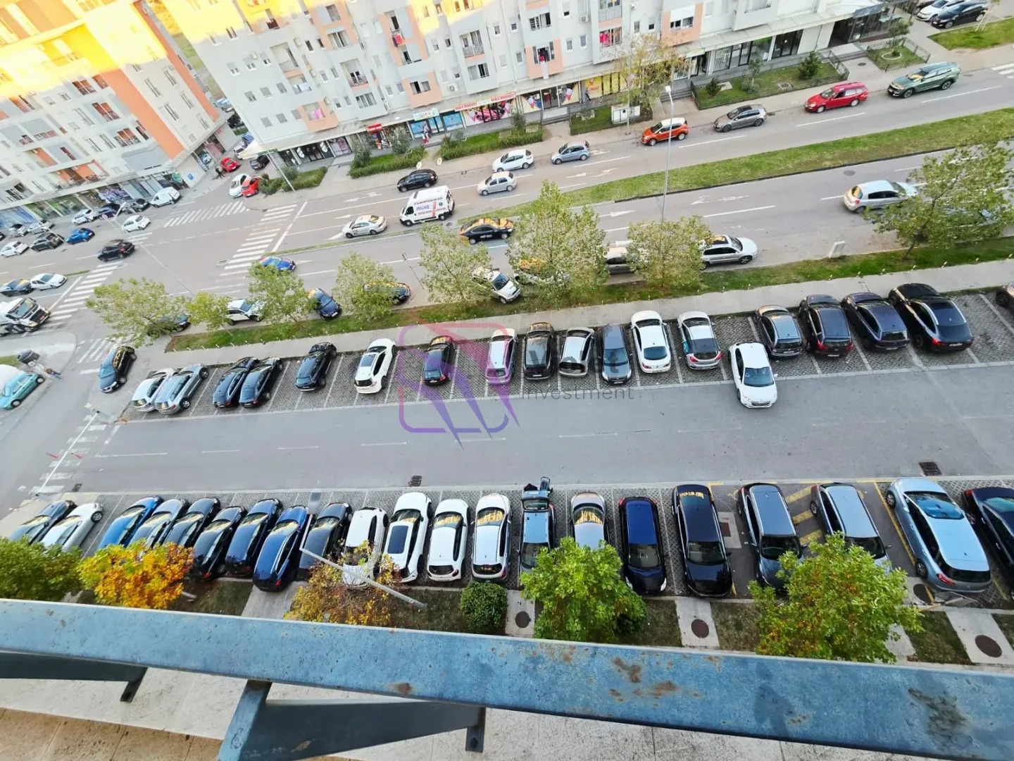 Pogled iz visine na gradsku ulicu i parking ispred zgrade.