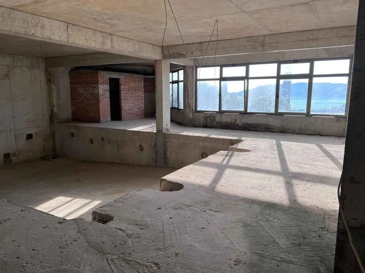 Unfinished bare-shell space under construction with concrete structures and windows.